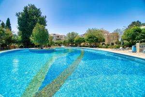 a large swimming pool with blue water at Hesperides Gardens 1 BED in Paphos