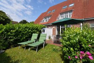 a group of green benches in front of a house at Inselrose in Langeoog