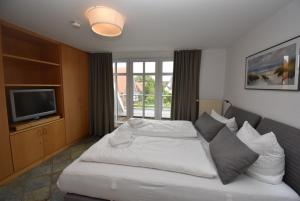 a bedroom with a large white bed and a television at Inselrose in Langeoog