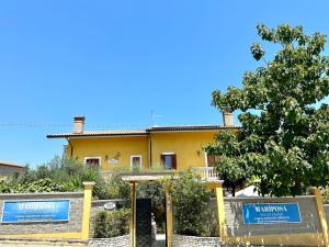 a yellow house with two blue signs in front of it at B&B Mariposa in Collecorvino
