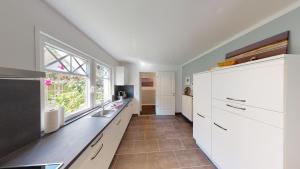 a kitchen with white cabinets and a sink and a window at Meedenhus 'VÖRN' in Langeoog +5 photos