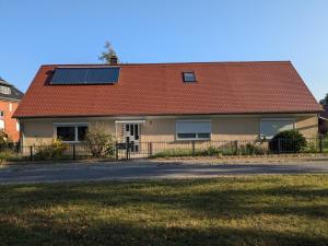 a house with a red roof with solar panels on it at Ferienwohnung Dorfaue in Lauta