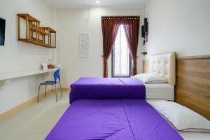 two beds in a room with purple sheets at Novon Family Hotel by Tripletree in Blimbing +49 photos