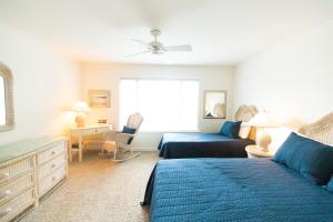 a bedroom with a blue bed and a couch at Seagrove Villa 5B - Oceanside Villa in the Trees in Isle of Palms +47 photos