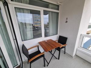 a table and chairs on a balcony with a window at Frische Brise FeWo 02 09 in Sahlenburg