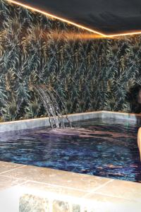 a fountain in a pool in front of a wall at Hôtel & Spa Rocabella in LʼÎle-Rousse