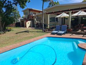 a swimming pool with two chairs and a house at Cedar Lodge Guest House in Robertson