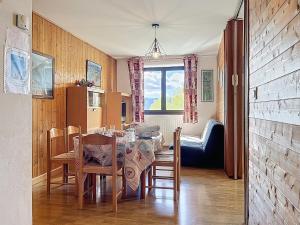 una sala da pranzo con tavolo, sedie e una finestra di Le Puigmal - Appartement deux Chambres - Parking - Wi-Fi a Font-Romeu