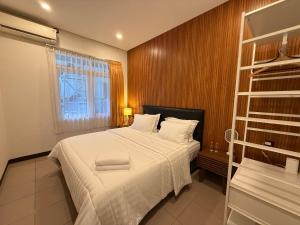 バンドンにあるThe Sakura House - Casa 99 Bandungの白いシーツと窓のあるベッドのある寝室 +21枚の写真