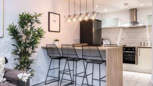 a kitchen with a bar with stools around it at Stylish Liverpool Apartment with Parking & Balcony in Liverpool