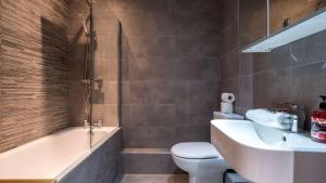 a bathroom with a tub and a toilet and a sink at Stylish Liverpool Apartment with Parking & Balcony in Liverpool