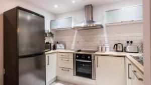 a kitchen with a stainless steel refrigerator and white cabinets at Stylish Liverpool Apartment with Parking & Balcony in Liverpool