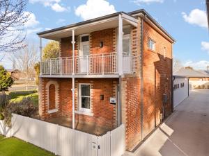 una casa de ladrillo con una valla blanca delante de ella en Sweet Seymour - 3 Bed 2 Bath Cosy & Modern Home, en Bathurst