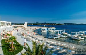 a beach with chairs and people on the water at Villa 11 Limoni in Sukošan