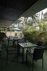 an outdoor patio with tables and chairs and palm trees at Trevon Hotels & Resorts Candolim Goa in Candolim