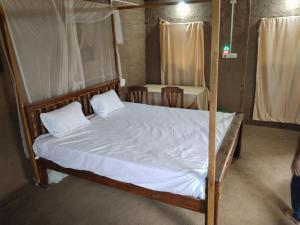 - une chambre avec un lit à baldaquin et des draps blancs dans l'établissement Shivalika home stay, à Maheshwar
