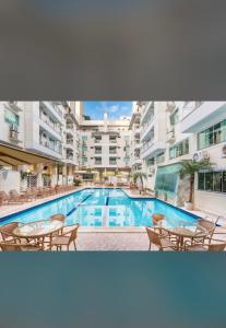 una piscina con tavoli e sedie di fronte a un edificio di Hotel y spa Summer Beach a Bombinhas