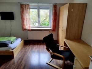 a bedroom with a desk and a bed and a window at Gästehaus Kreuz in Blaustein