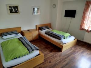 two beds in a room with wooden floors at Gästehaus Kreuz in Blaustein