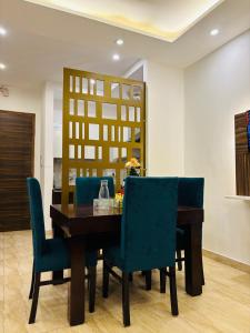 a dining room with a wooden table and blue chairs at Gharonda - Your Cozy Nest in Jāmb