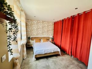 a small bedroom with red curtains and a bed at La Kaz Eden * * * * in Les Cocos +17 photos