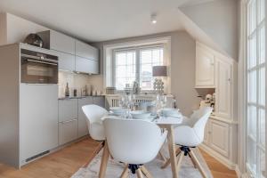 a white kitchen with a table and white chairs at Wattküken in Munkmarsch