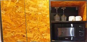 a microwave with bottles and glasses on a wall at Kalo Shipping Container in Christiansborg