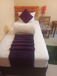 Cama grande con sábanas blancas y almohadas moradas en Salvie Geust Inn, en Kasane Airport