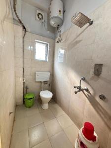 La salle de bains est pourvue de toilettes et d'un seau vert. dans l'établissement Hotel Aditya Guwahati, à Guwahati