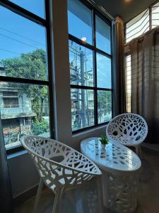 2 chaises blanches et une table devant une fenêtre dans l'établissement Hotel Aditya Guwahati, à Guwahati