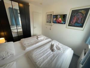 a bedroom with two beds with white sheets at Fewo 4 OG Sylt Westerland in Süderende +14 photos