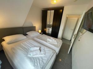 a bedroom with a white bed with towels on it at Fewo 4 OG Sylt Westerland in Süderende