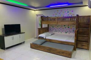 a bedroom with a bunk bed and a flat screen tv at Michael's Homestay - Farm Villa near Patar Beach & Bolinao Falls in Bolinao