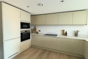 a white kitchen with white cabinets and appliances at Paramount Stays - Uxbridge in Uxbridge