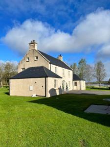 a large white building with a black roof on a grass field at The Lough Erne House at Golf Village Lough Erne Resort in Enniskillen