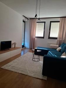 a living room with a blue couch and a rug at Apartman Atlas in Doboj