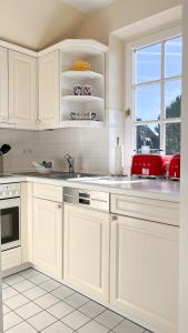 une cuisine blanche avec des armoires blanches et une fenêtre dans l'établissement Heefwai 2 - W4, à Morsum