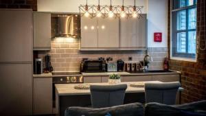 a kitchen with white cabinets and a table with chairs at Central Warehouse Apt - Sleeps 8, Pet Friendly in Liverpool