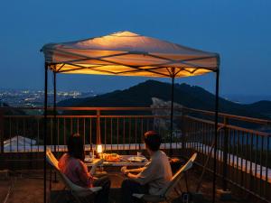 three people sitting at a table under an umbrella at 名田忠山荘 in Tatsuno