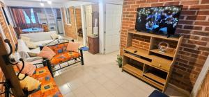 ein Wohnzimmer mit Fernseher und einer Ziegelwand in der Unterkunft El Corazón de Villa in Villa del Carbón