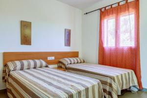 una stanza con due letti e una finestra di Villa Datil by Villa Plus a Es Mercadal