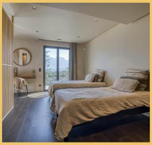 a bedroom with two beds and a large window at Maison Gokan I Grand Annecy in Sévrier