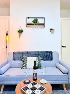 a blue couch with two wine glasses on a table at Spacious 4-Bedroom Newcastle, Sleeps 7 Guests in Kimbolton