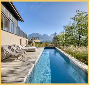 a swimming pool with chairs on a wooden deck at Maison Gokan I Grand Annecy in Sévrier