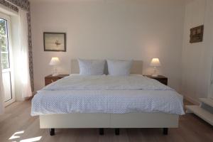 a bedroom with a large white bed with two lamps at Welkimen tüs 1-Tradition in Oldsum
