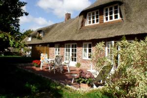 a house with a table and chairs in front of it at Welkimen tüs 1-Tradition in Oldsum
