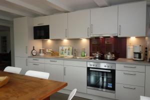 a kitchen with white cabinets and a wooden table at Welkimen tüs 2-Moderne in Oldsum