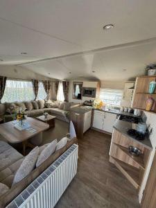 a large living room with a couch and a kitchen at Pinewoods Holiday Park - Holiday Accommodation 21638 in Wells next the Sea