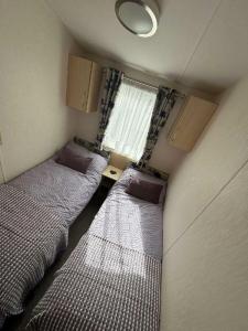 two beds in a small room with a window at Pinewoods Holiday Park - Holiday Accommodation 21638 in Wells next the Sea +11 photos