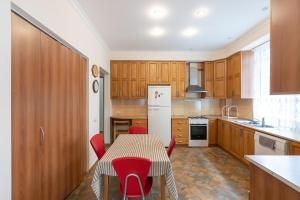 une cuisine avec des placards en bois et une table avec des chaises rouges dans l'établissement Vake Charm Residence, à Tbilissi